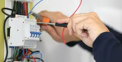 Electrician installing and adjusting circuit breakers in an electrical panel in Buffalo, NY