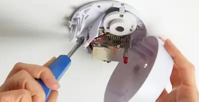 Certified technician wiring smoke detector during installation in Buffalo, NY